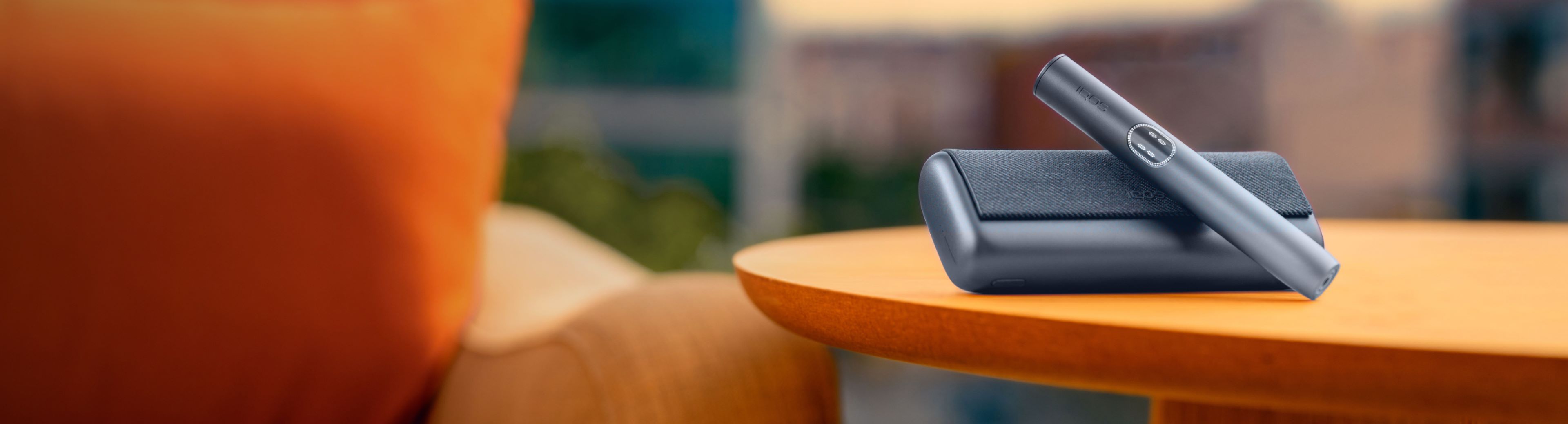 IQOS ILUMA i Holder liegt auf einem Charger auf einem Tisch.