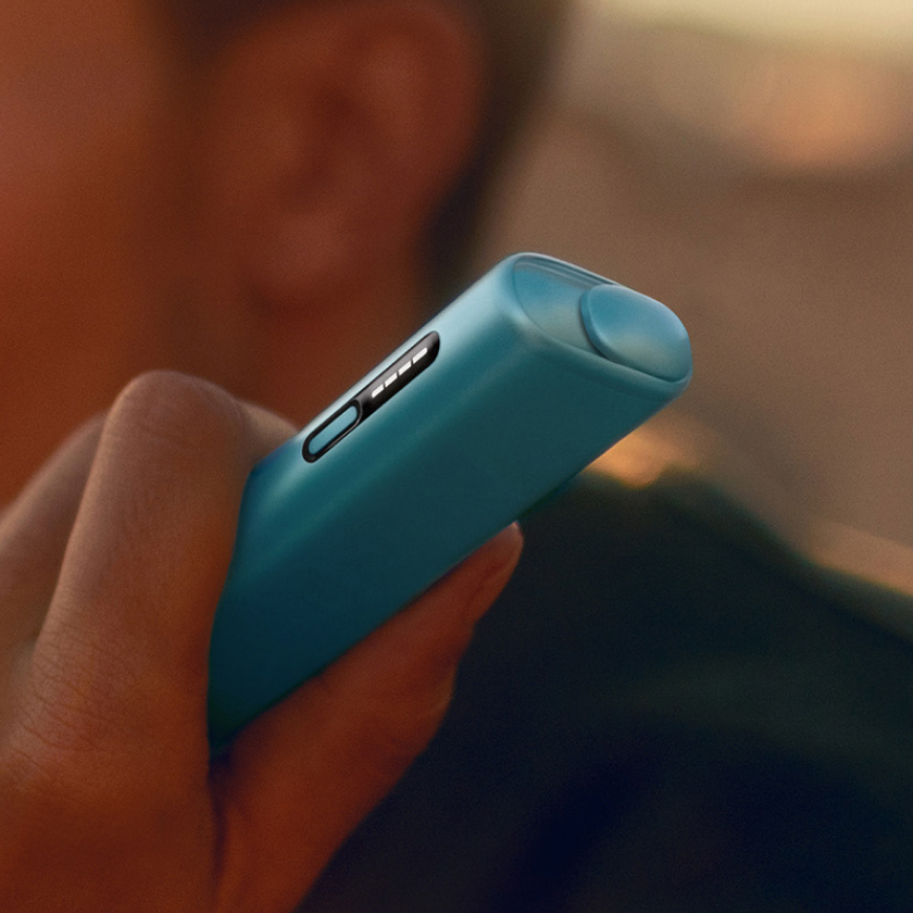 Детальный вид руки, держащей синее устройство IQOS ILUMA i ONE
