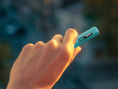 Рука держит синее устройство IQOS ILUMA i ONE