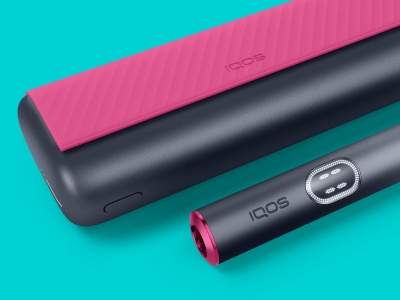 Красное и чёрное устройство IQOS ILUMA i PRIME и его зарядное устройство на светло-бирюзовом фоне