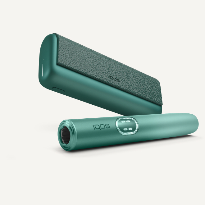 Устройство IQOS ILUMA i PRIME цвета «зелёный аспен» под зарядным устройством