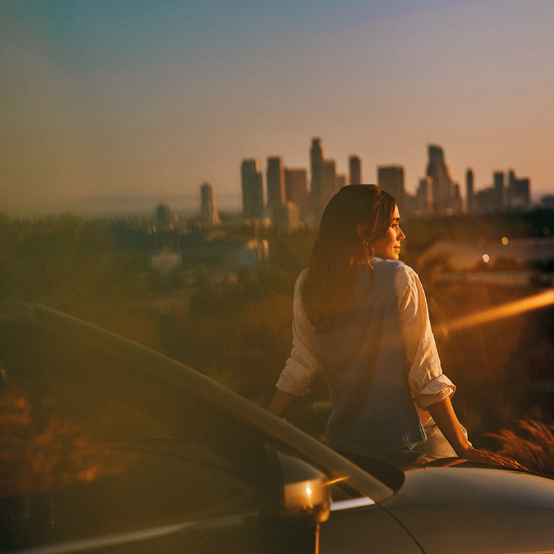 Mujer viendo el atardecer de una ciudad