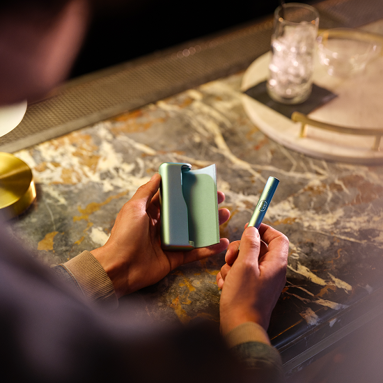 Persona sosteniendo en sus manos un IQOS ILUMA i PRIME en color Breeze Blue