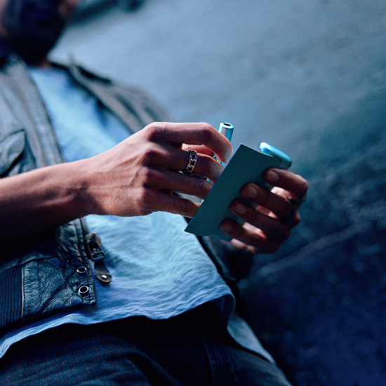 Hombre sosteniendo en sus manos un IQOS ILUMA i PRIME en color Breeze Blue