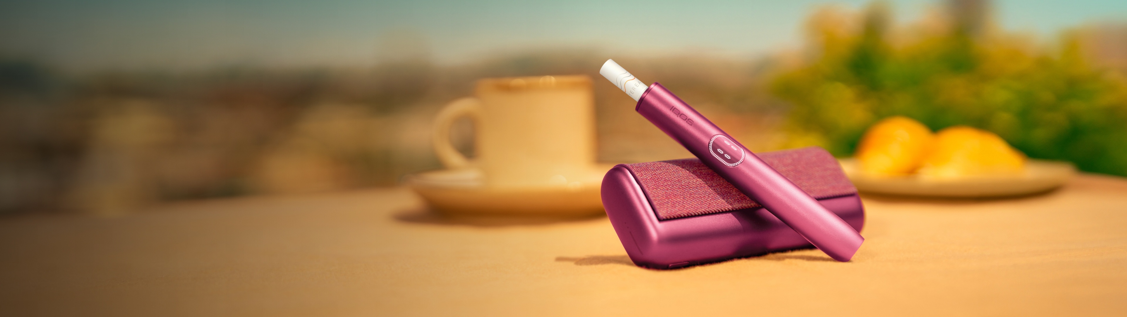 Garnet Red IQOS ILUMA i PRIME device above its charger