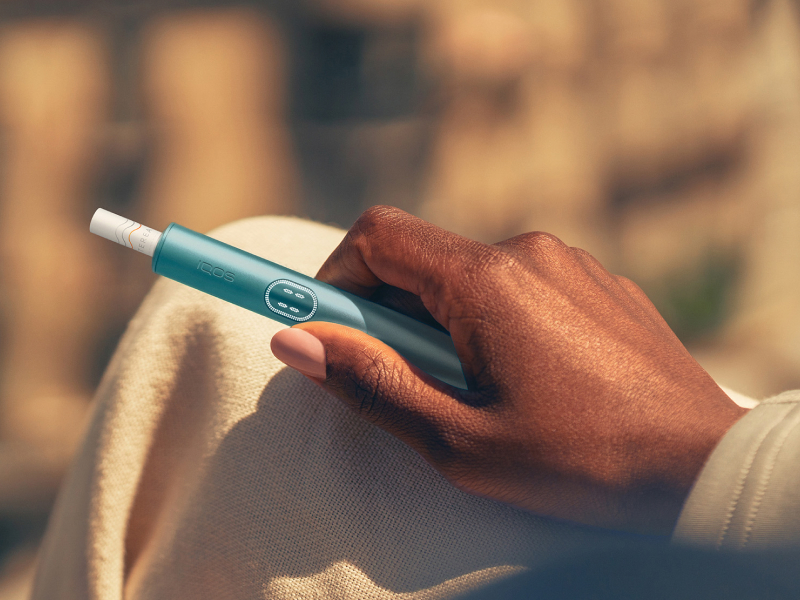 Hand holding a blue IQOS ILUMA i PRIME device