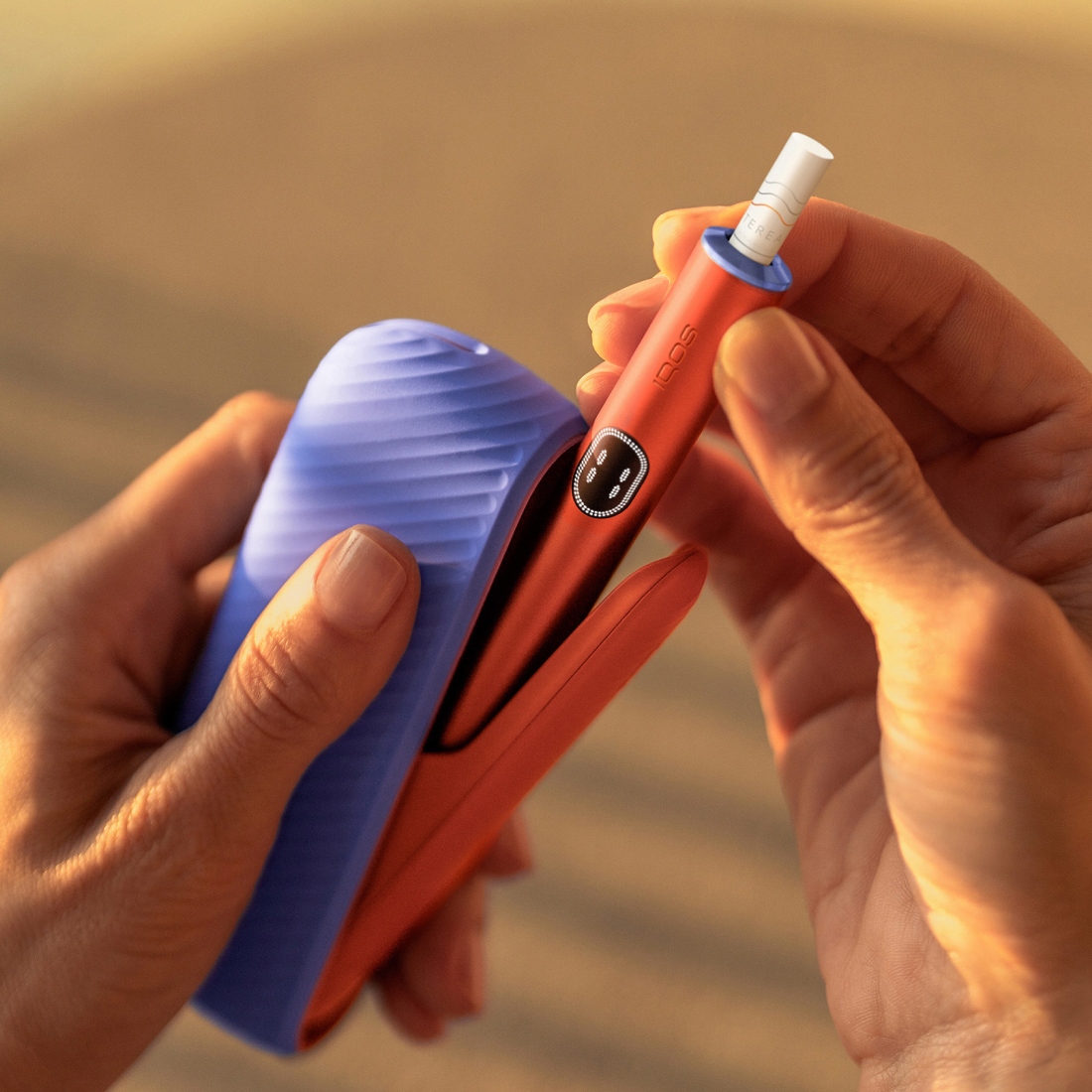 يتم إخراج جهاز IQOS ILUMA i من الشاحن الخاص به، مع باب وحلقات مخصصة