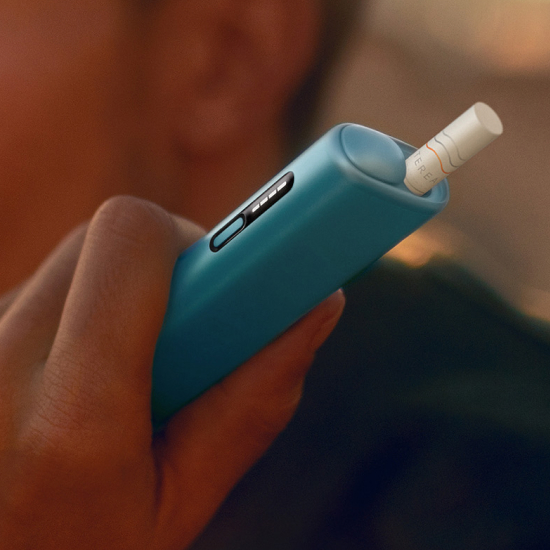 تفاصيل يد تحمل جهاز IQOS ILUMA i ONE أزرق اللون.