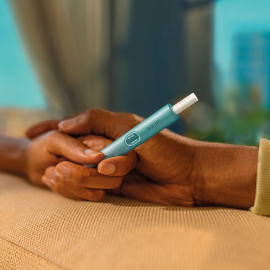 Two hands holding together an IQOS ILUMA i PRIME device