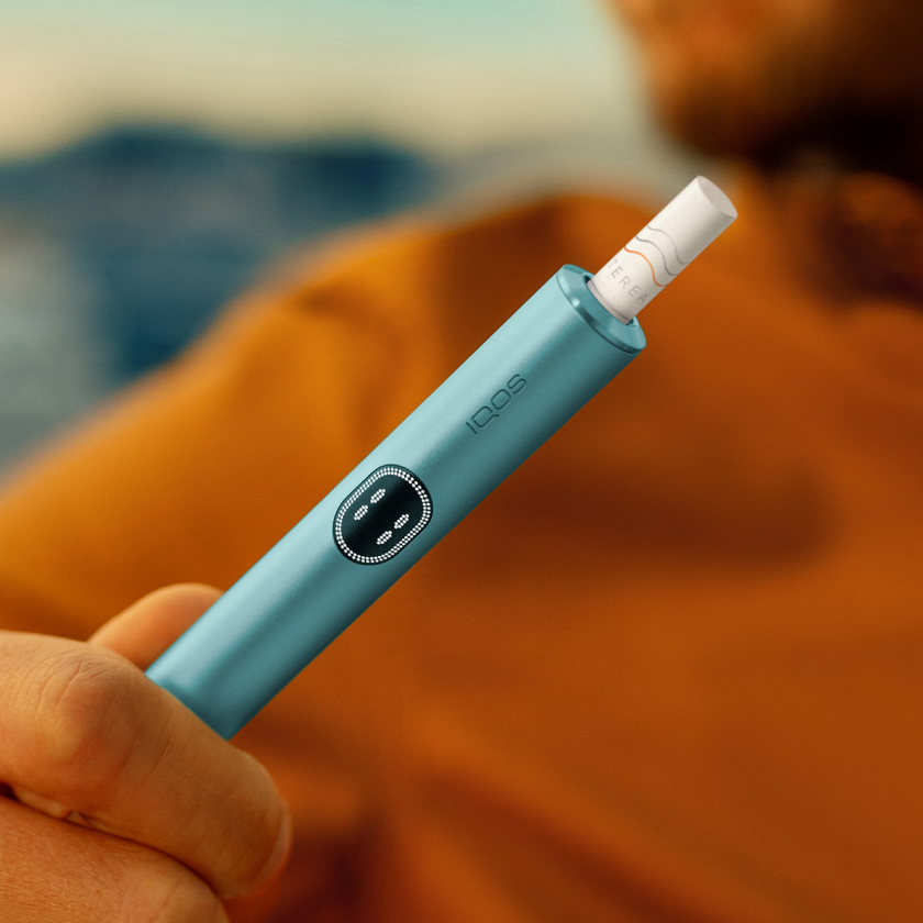 Hand holding a blue IQOS ILUMA i device