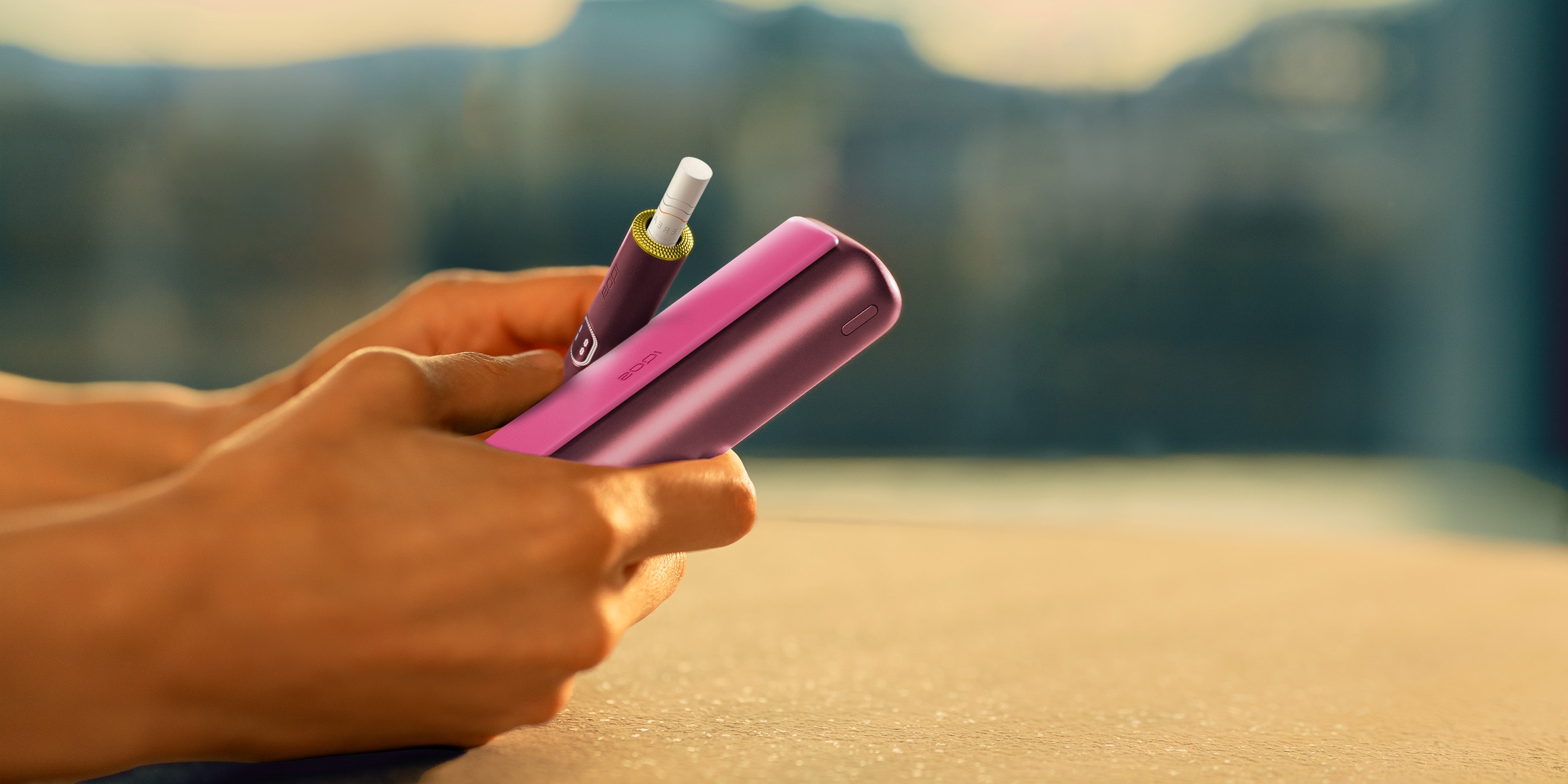 Blue IQOS ILUMA i PRIME device above its charger, customized with wrap and rings