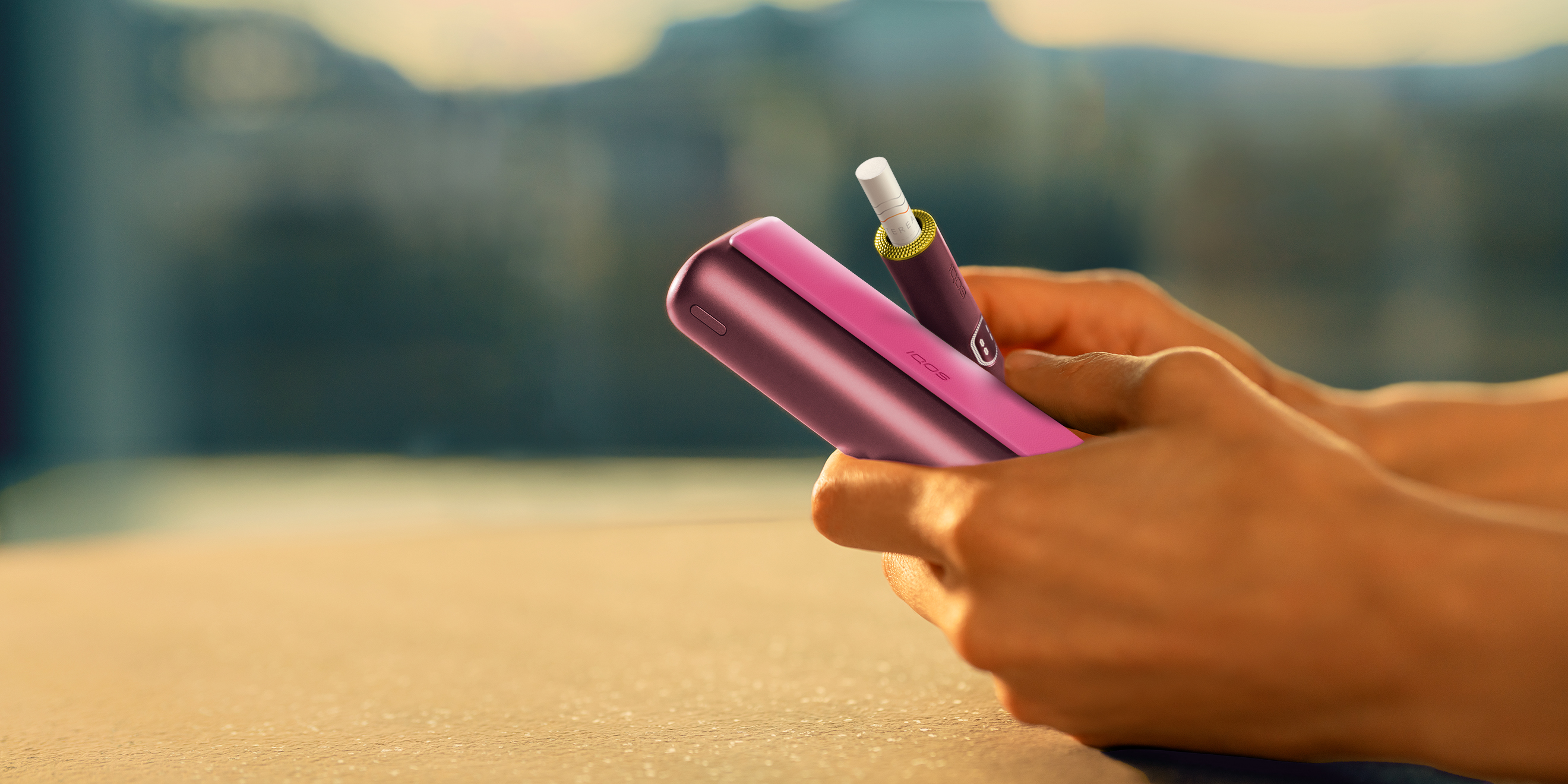 Blue IQOS ILUMA i PRIME device above its charger, customized with wrap and rings