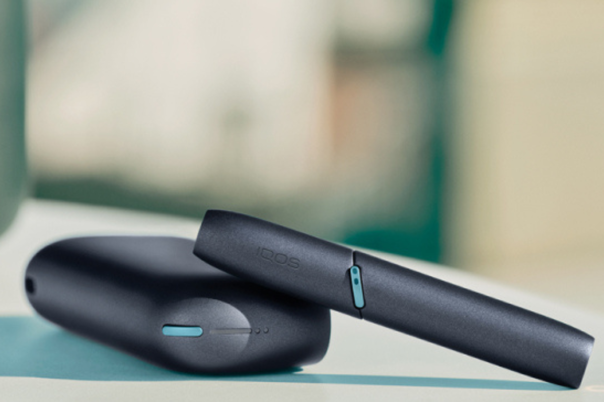 Un kit IQOS ORIGINALS DUO Ardoise posé sur une table avec un fond flouté
