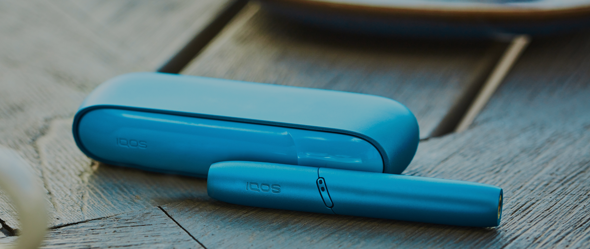 Un Kit IQOS ORIGINALS DUO Turquoise posé sur une table en bois