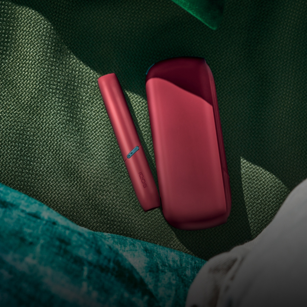 Un Kit IQOS ORIGINALS DUO SCARLET posé sur un tissu vert