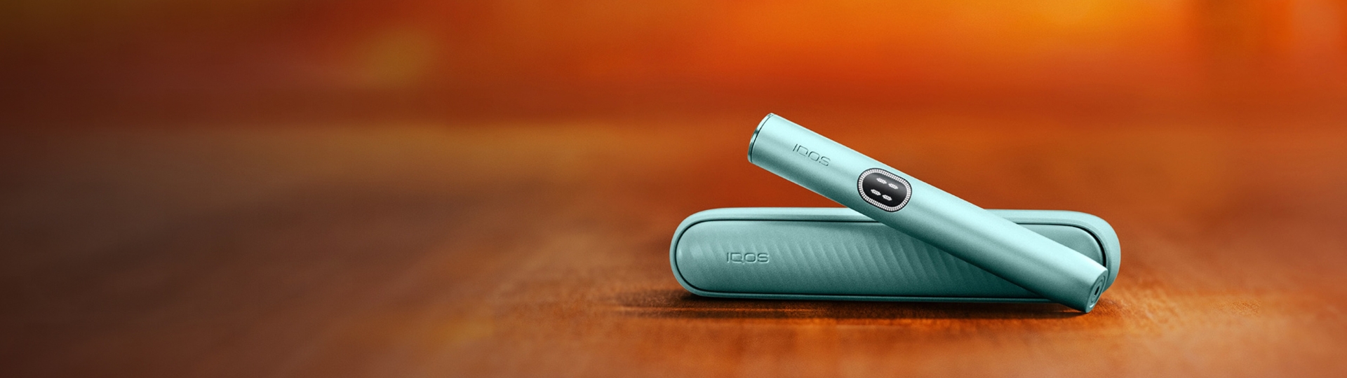 IQOS Iluma i couleur aigue marine posée sur fond orange