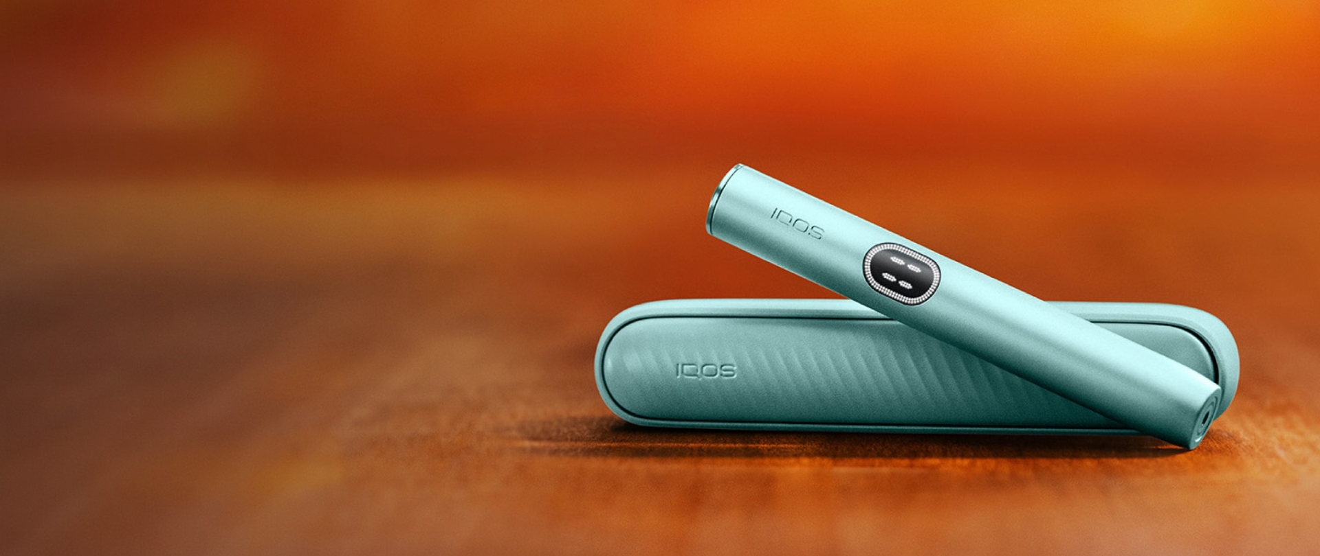 Iqos iluma i mid couleur aigue-marine sur fond orangé.