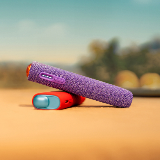 2 appareils IQOS ILUMA i ONE (appareil tout-en-un) couleurs Terracotta et Aigue-Marine, posés l'un sur l'autre, sur un fond dégradé orange. Chaque appareil est protégé par une coque de protection. L'appareil couleur Aigue-Marine a une coque rouge et l'appareil couleur Terracotta a une coque violette.