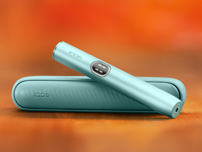 Appareil IQOS ILUMA i (stylet + chargeur de poche) couleur Aigue-Marine sur un fond dégradé orange
