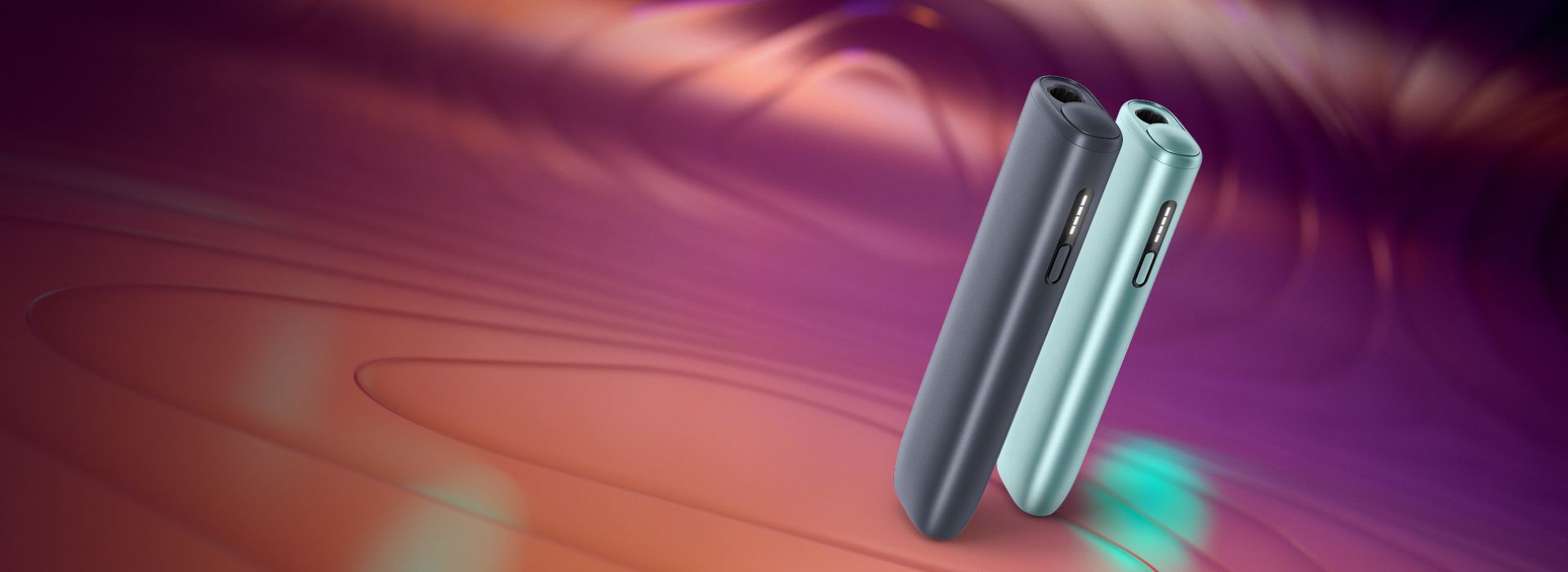 Deux Appareils IQOS ILUMA i One couleur Aigue-Marine et terracotta posés sur un fond dégradé orange.