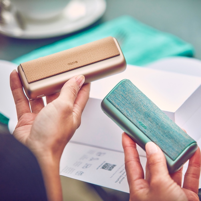 Two people holding IQOS Iluma Prime devices