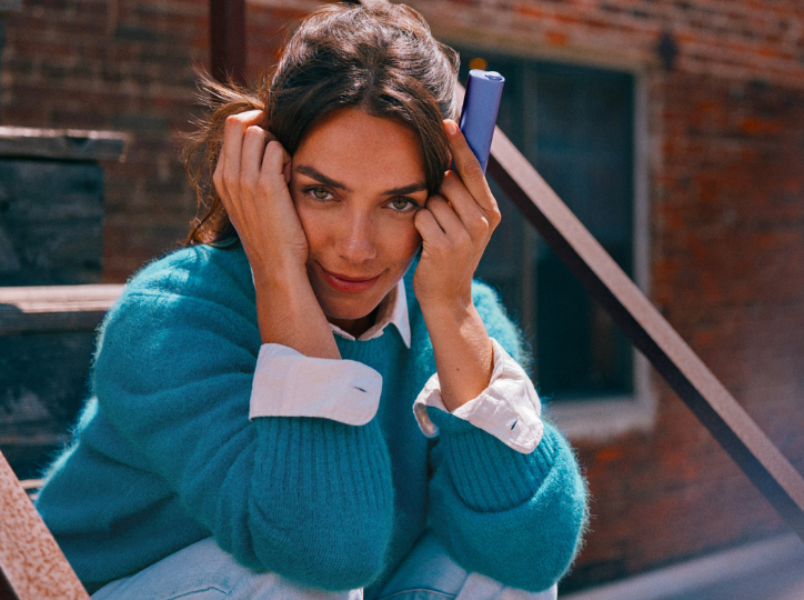 Jemand hält ein IQOS ILUMA i PRIME neben einem Smartphone