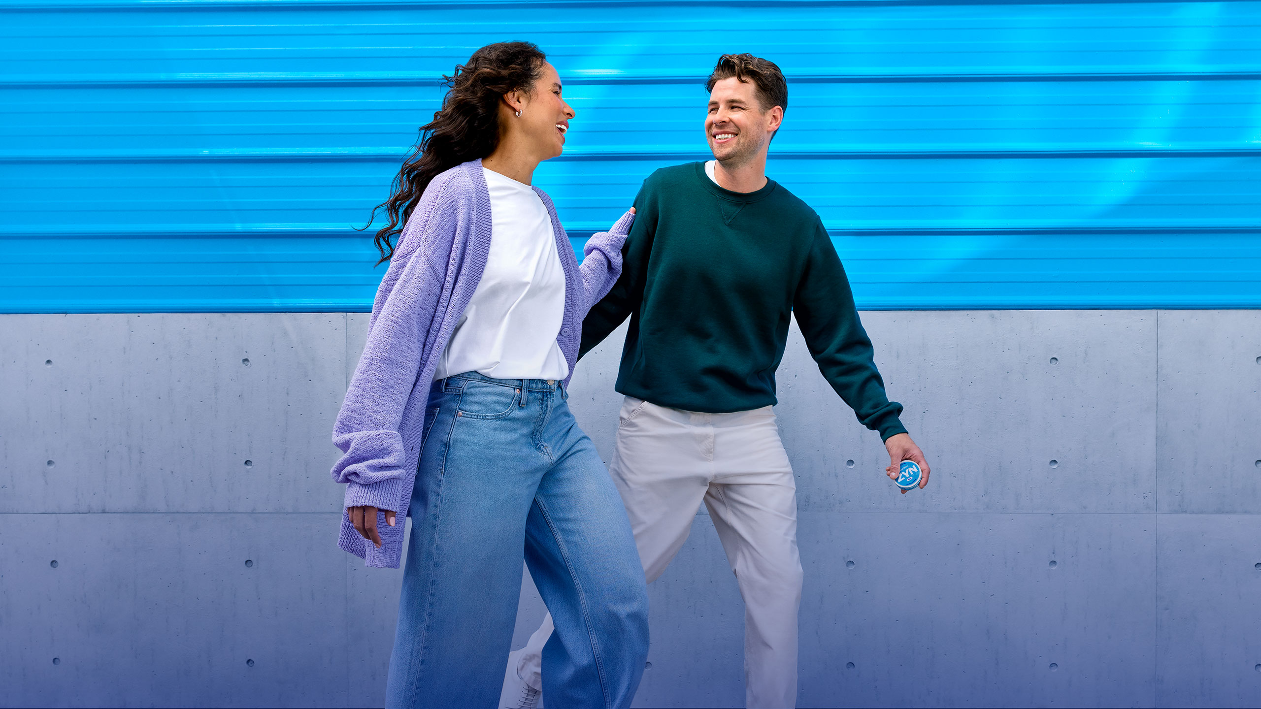 Woman with headphones and a green bag walking in front of a ZYN logo