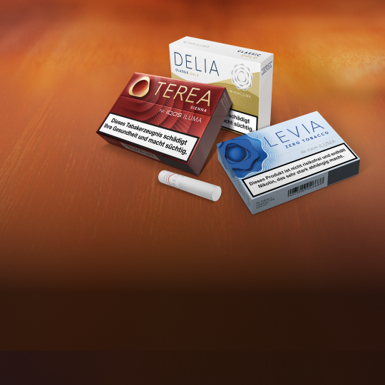 Je eine Packung TEREA Tabaksticks, DELIA Tabaksticks und LEVIA Nikotinsticks liegen auf einer braunen Holzplatte.
