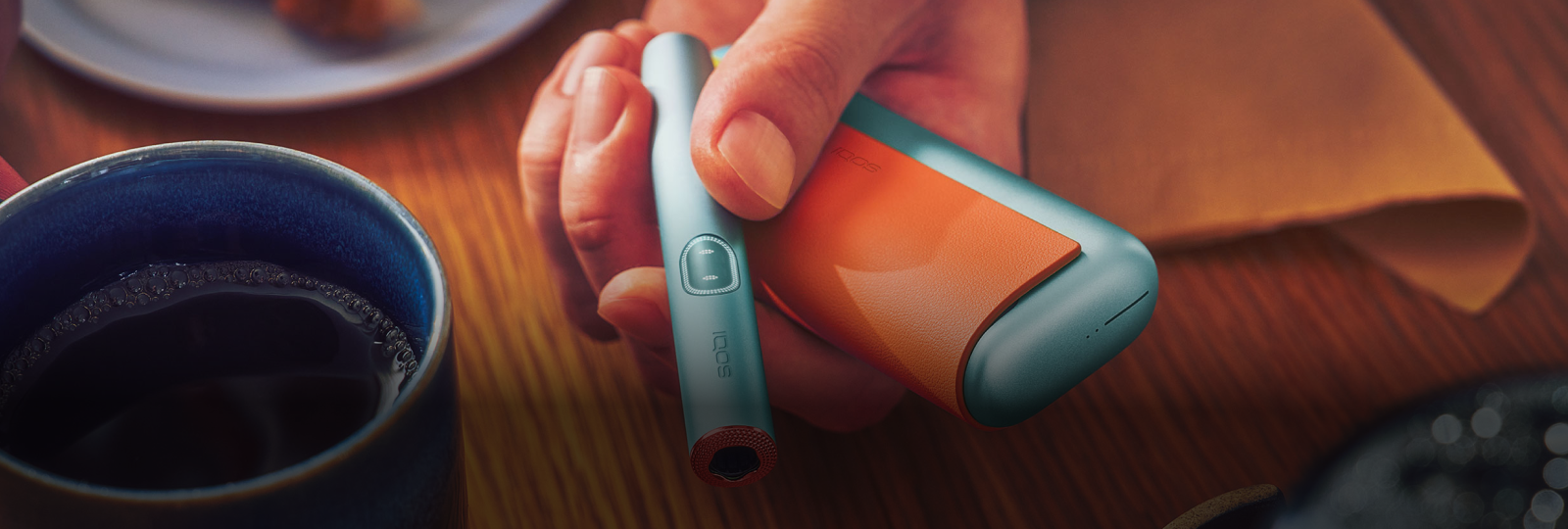 Eine Hand hält ein IQOS mit Accessoires ausgestattet.