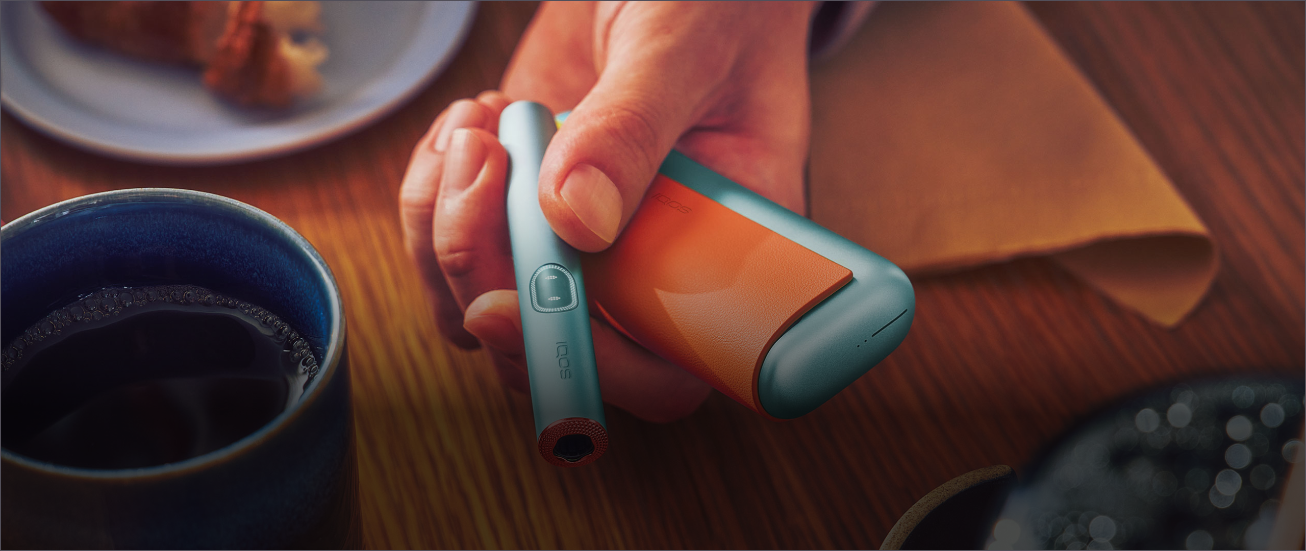 Eine Hand hält ein IQOS mit Accessoires ausgestattet.