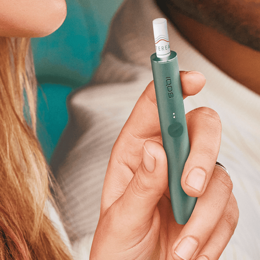 Frau hält einen IQOS Holder mit einem Stick im Holder