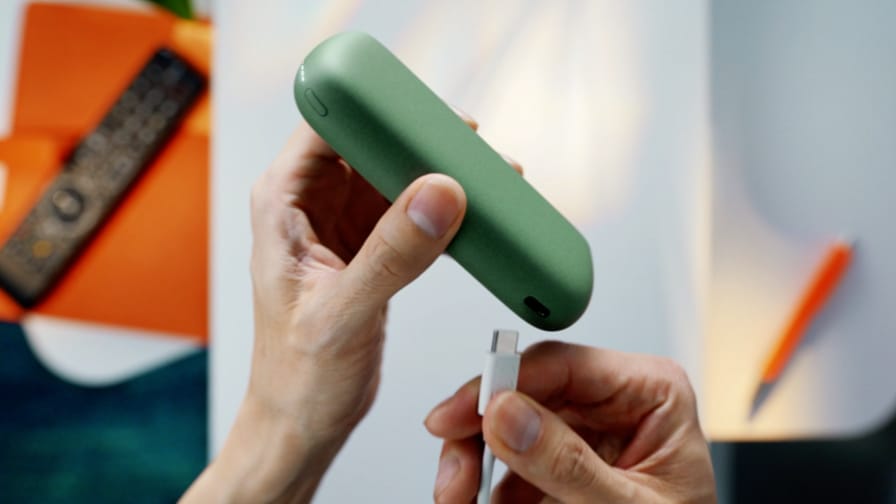 Jemand schließt ein jadegrünes IQOS ILUMA PRIME Gerät an ein Ladegerät an