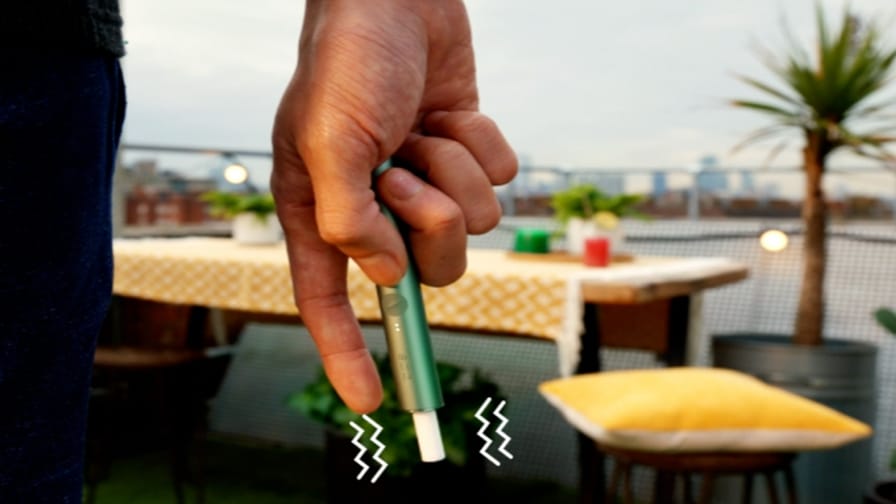 Jemand hält ein jadegrünes IQOS ILUMA PRIME Gerät in der Hand