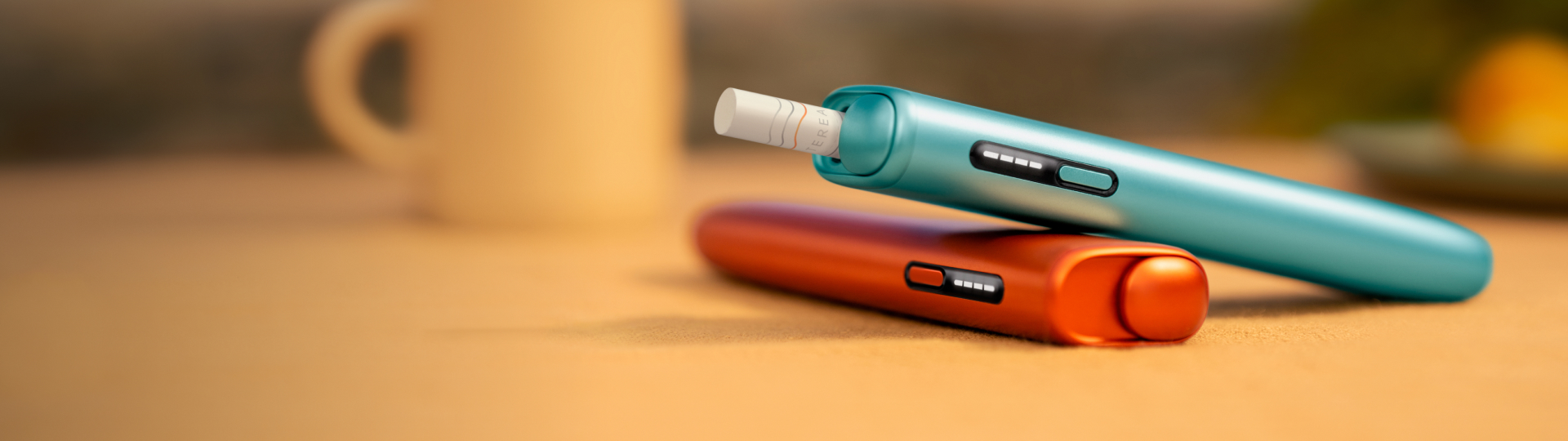Zwei IQOS ILUMA i ONE Tabekerhitzer dargestellt auf einem Holztisch.