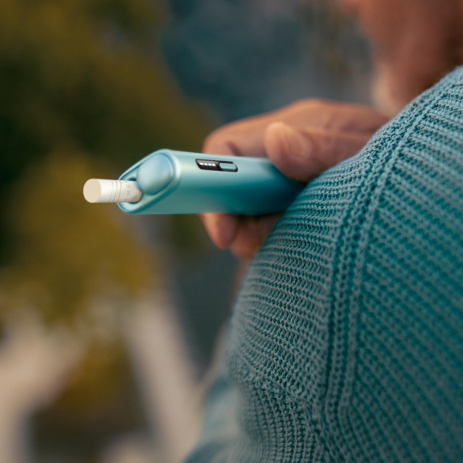 IQOS ILUMA i Tabakerhitzer liegend auf einem Holztisch.