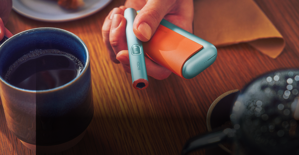 IQOS ILUMA i mit Accessoires wird von einer Person in die Kamera gehalten