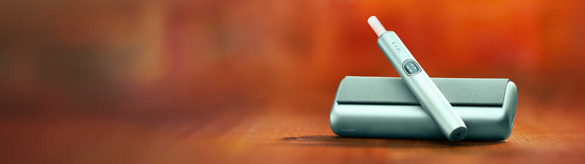 IQOS ILUMA i in der Farbe Breeze Blue abgebildet vor einem orangefarbenen Hintergrund.