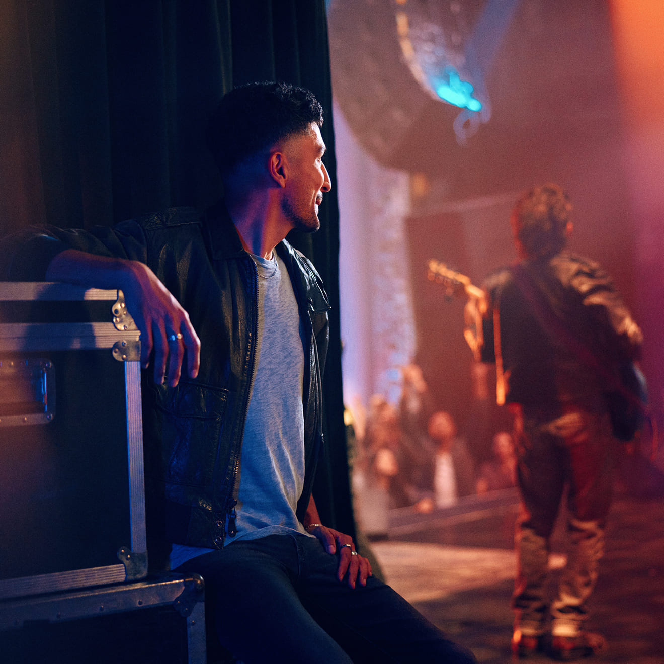 Hombre sentado viendo a un guitarrista tocar