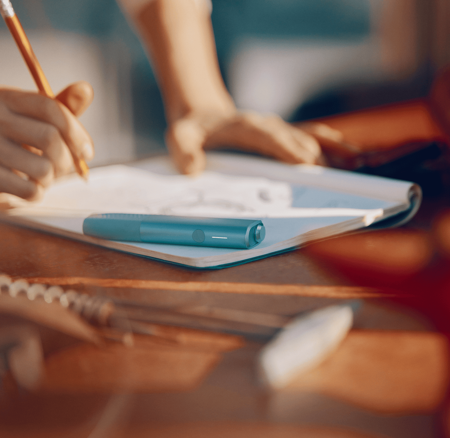 IQOS ILUMA i ONE color breeze blue sobre un cuaderno