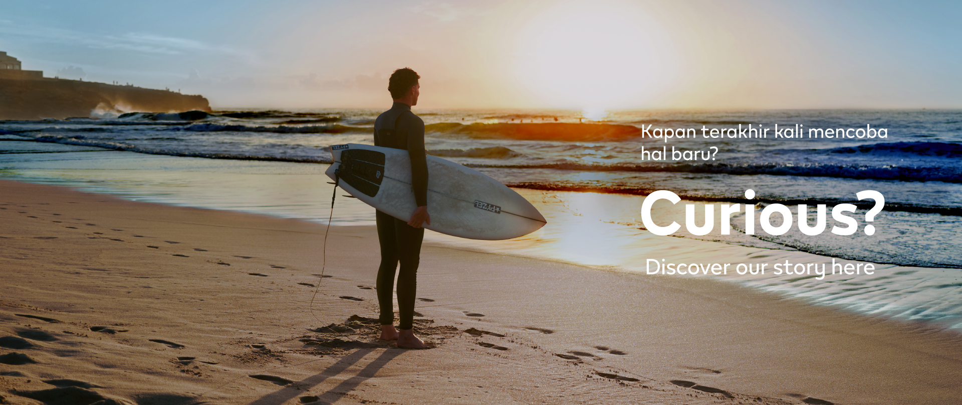 Banner Stay Curious IQOS – Seorang pria memegang papan selancar di pantai