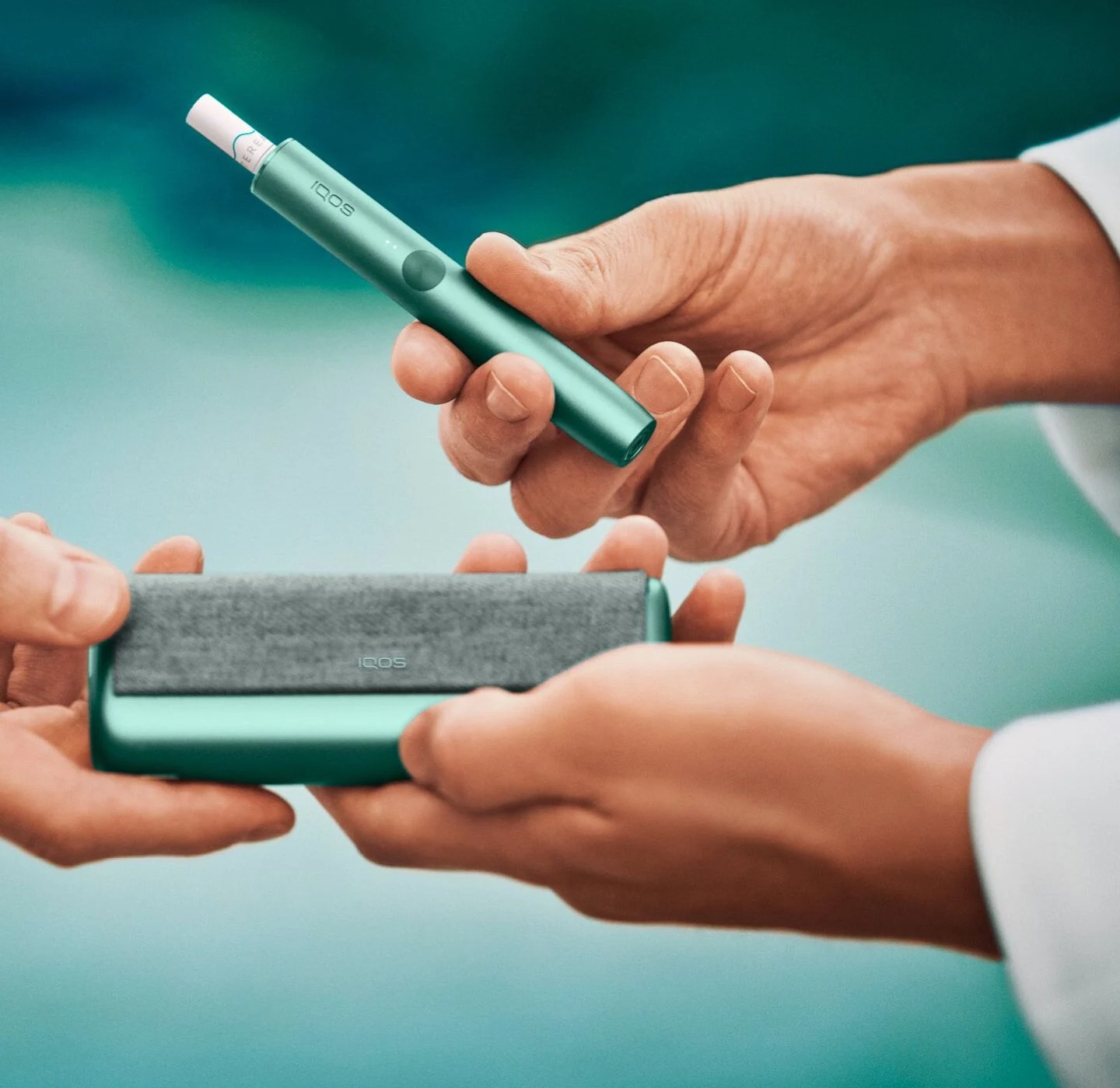 Close up of a chef's hands opening a jade green IQOS ILUMA device.