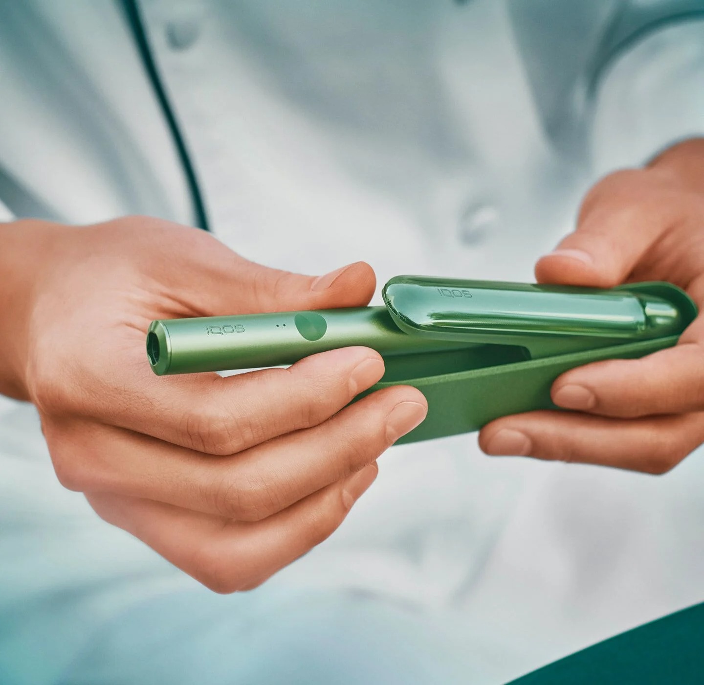Close up of a chef's hands opening a jade green IQOS ILUMA device.