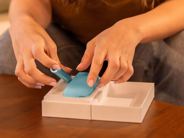 A person holding an unopened IQOS device box.