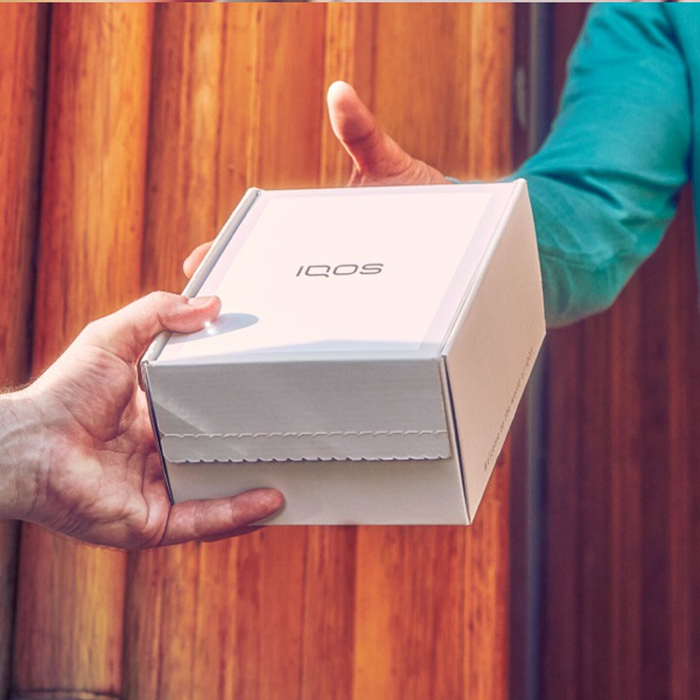 Someone handing over an IQOS box