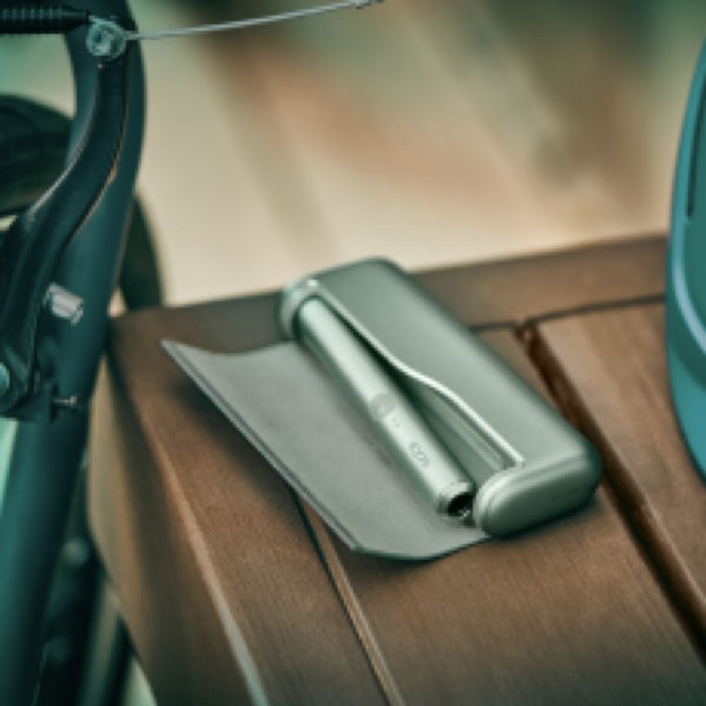 A Jade Green IQOS ILUMA PRIME Holder and Pocket Charger in a person's hands.