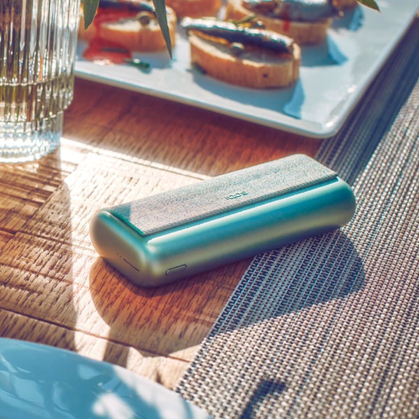 Green IQOS ILUMA PRIME Pocket Charger on a table.