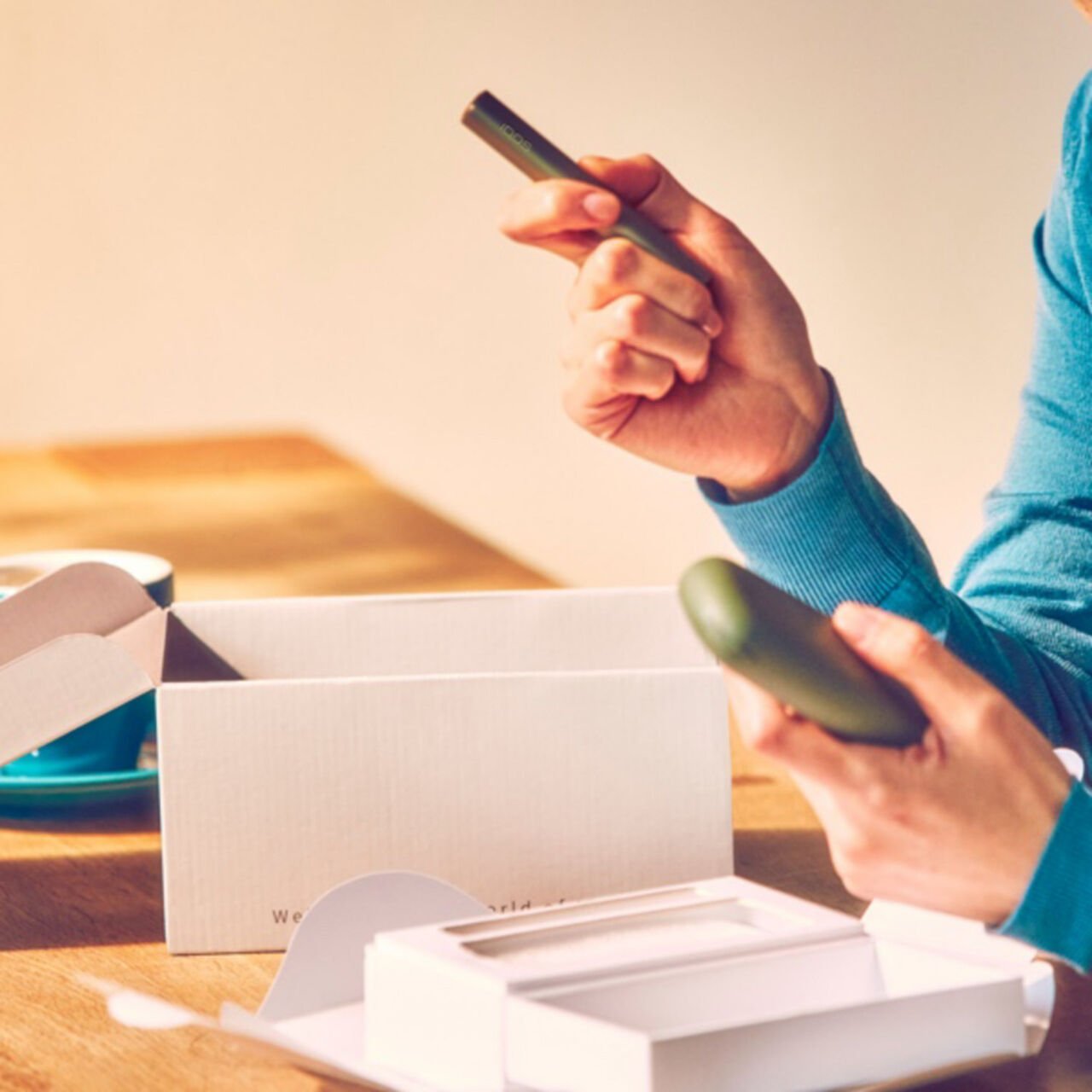 A person with an IQOS ILUMA Pocket Charger and Holder.