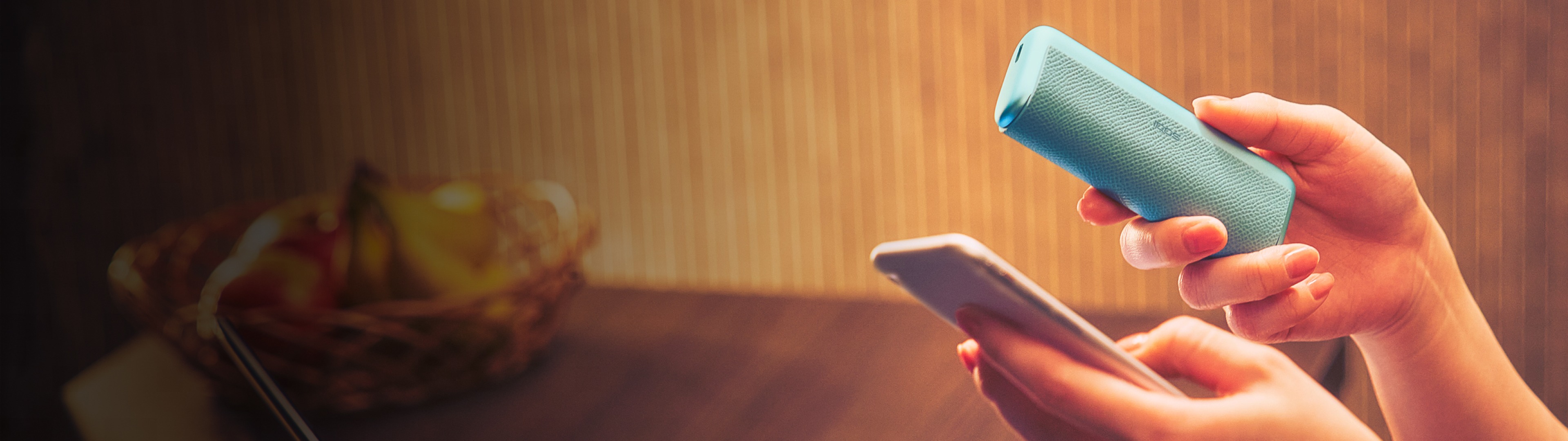 Mains tenant un appareil IQOS ILUMA bleu et un téléphone