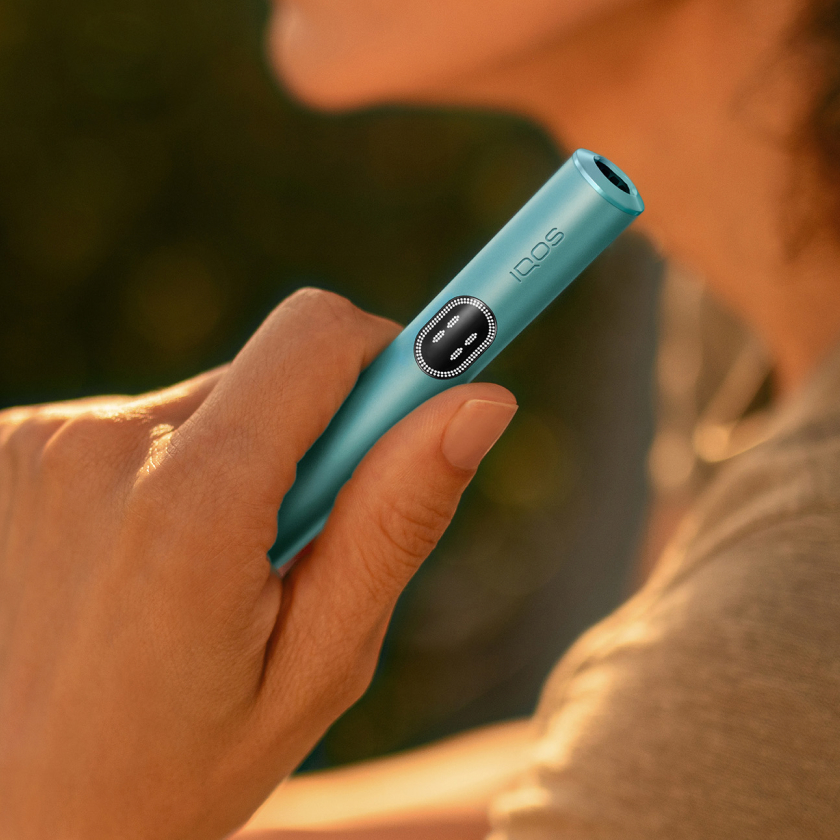 A person holding a Breeze Blue IQOS ILUMA i device.