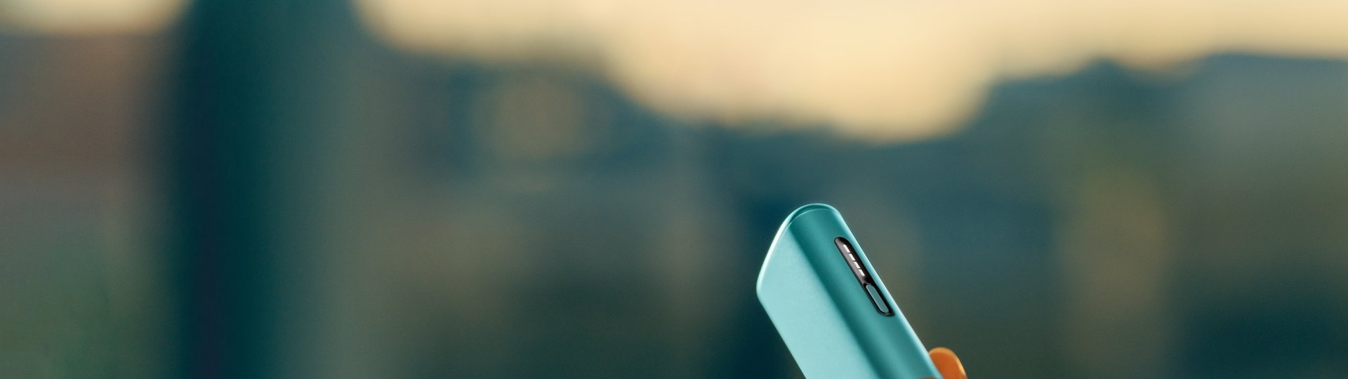 A person holding a Breeze Blue IQOS ILUMA i ONE.